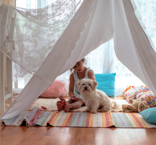 girl and dog in a blanket fort