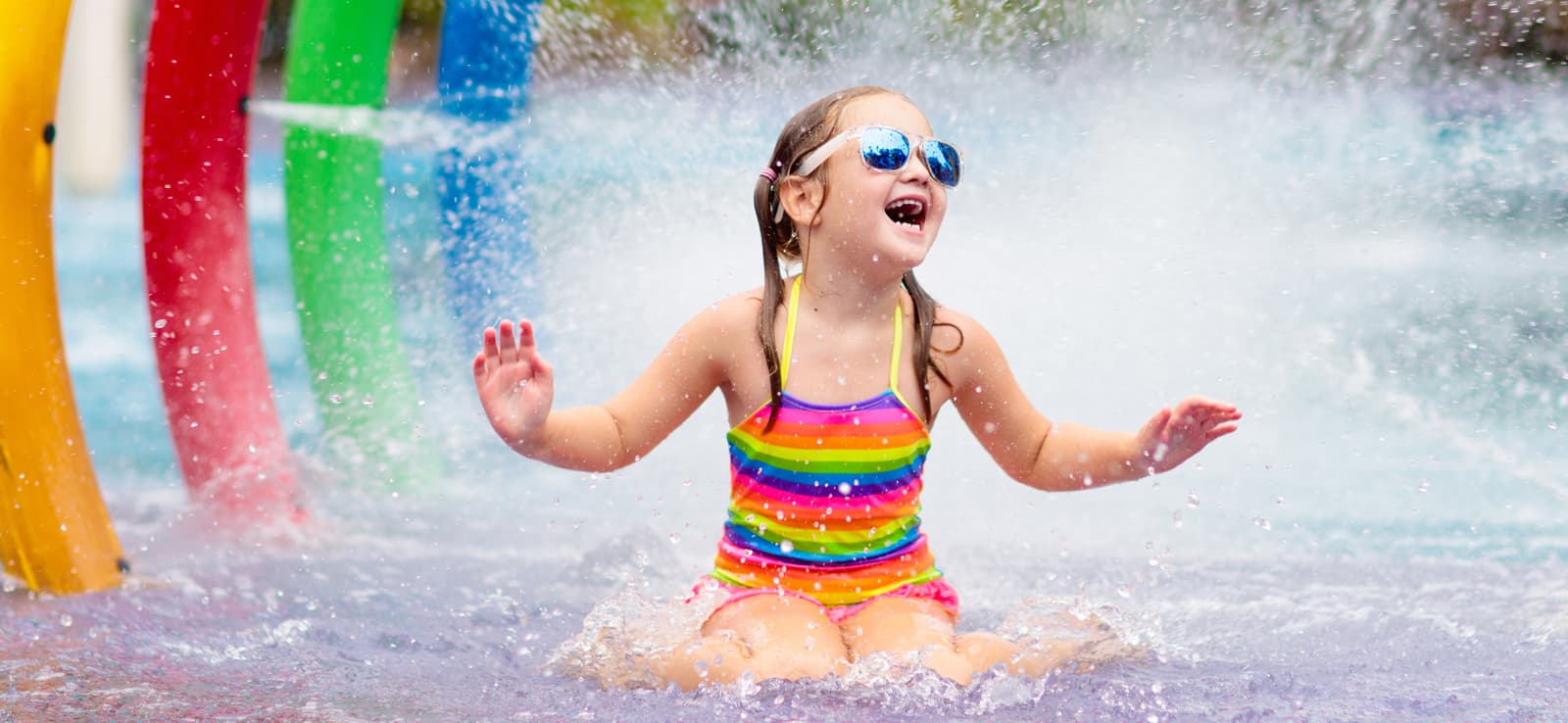girl wearing sunglasses getting splashed at waterpark
